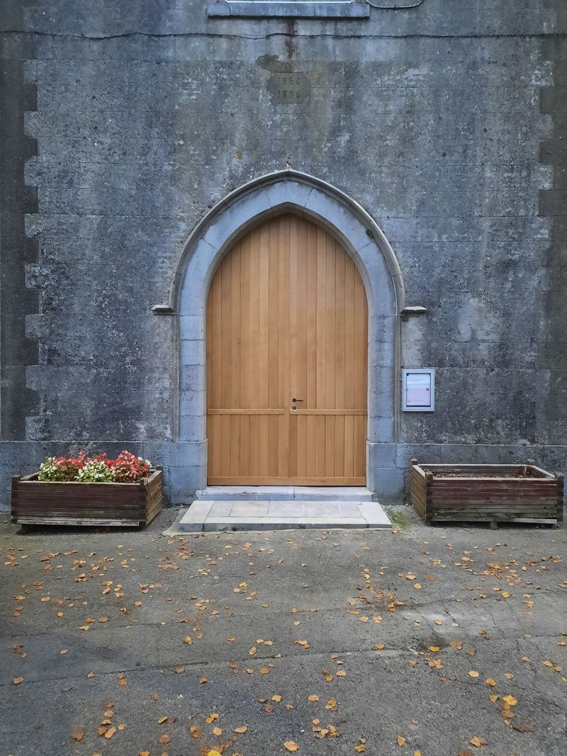 Porte en bois en ogive dans une façade en pierre – Guillaume Menuiserie